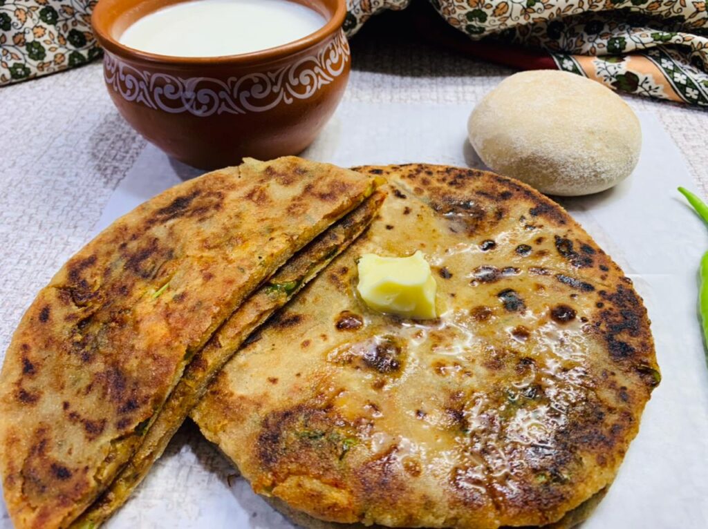 In the image there is aloo paratha with butter and curd. 