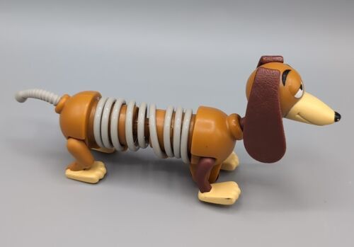 A Slinky J.D. the Dog
toy from the Toy Story franchise Burger king. The toy is a dachshund with a brown body, floppy ears, and a gray slinky for a middle section. The toy is posed on its side, with its tail curled.
